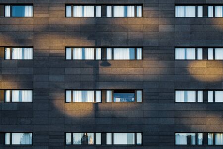 Afternoon light over the black facade of an urban building with long horizontal windowsの写真素材