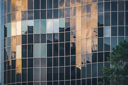 Afternoon lights reflected on the curved glass facade of an office buildingの写真素材