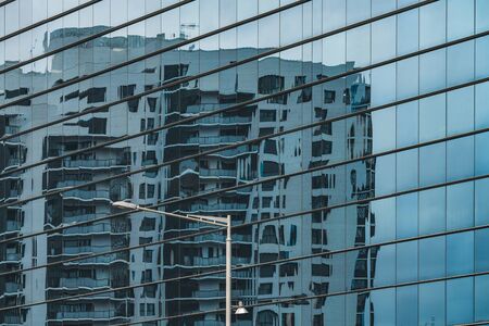 Urban residential building reflected in a blue glass facadeの写真素材