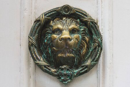 Antique door knocker made of iron representing a lion's headの写真素材