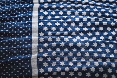 Detail of a crumpled shawl in blue with white polka dots and tiny flowers creating a patternの写真素材
