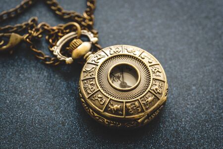 Detail of a metal pocket watch with horoscope design