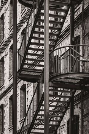 Exterior metal stairs of an old restored factory in warm black and whiteの写真素材