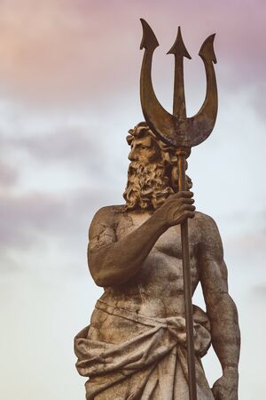 Sculpture of Neptune with trident under the sunset skyの写真素材