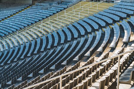 Rows of empty seats of a large stadium on sunny day before sports eventの写真素材