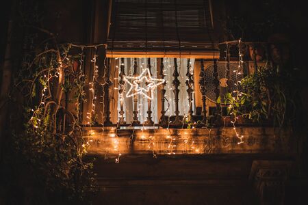 A light star hanging on a balcony decorated with light garlands at nightの写真素材