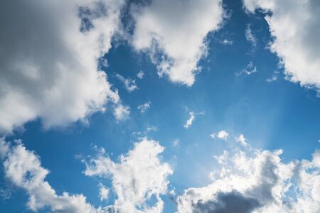 Sun shining through cumulus clouds in a blue skyの写真素材
