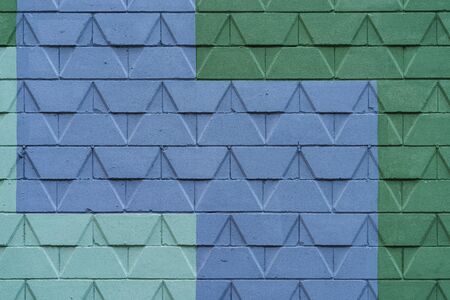 Detail of a street wall with geometric pattern design painted in blue and two different tones of...