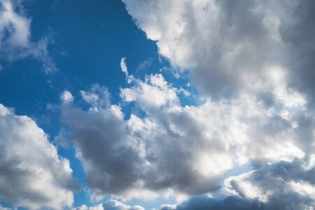 Sun shining through cumulus clouds in a blue skyの写真素材