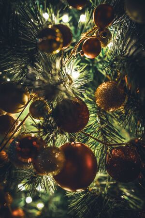 Traditional Christmas tree garland with baubles hanging on illuminated branches at nightの写真素材