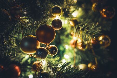 Traditional Christmas tree garland with baubles hanging on illuminated branches at nightの写真素材