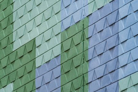 Detail of a street wall with geometric pattern design painted in blue and two different tones of greenの写真素材