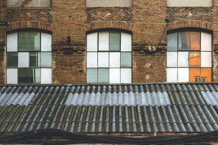 Windows and worn-out roof of an old abandoned textile factory at the afternoon lightの写真素材
