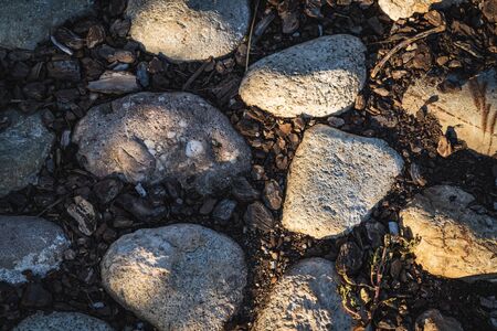 Detail of a cobblestone ground path with boulders and cork bark at the afternoon lightの写真素材