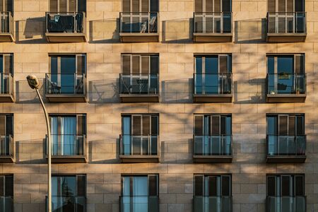 Shadows of modern balconies over a stone facade at the afternoon lightの写真素材