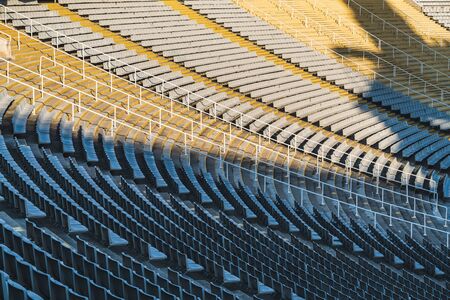 Rows of empty seats of a large stadium on sunny day before sports eventの写真素材