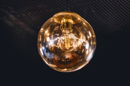 Giant vintage style light bulb lit with its retro filaments visible insideの写真素材