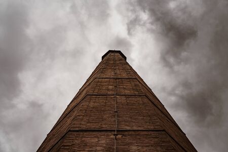 Smokestack of an old factory under a stormy skyの写真素材