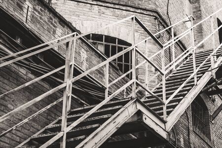 Exterior metallic stairs of an old abandoned textile factory in black and whiteの写真素材