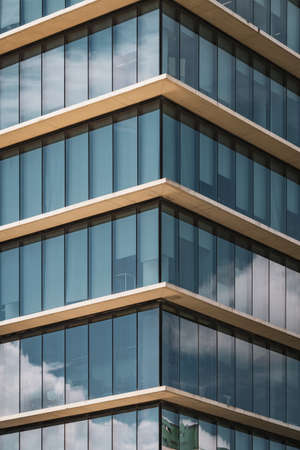 Symmetrical view of the corner of an office building with vertical glazed windowsの写真素材