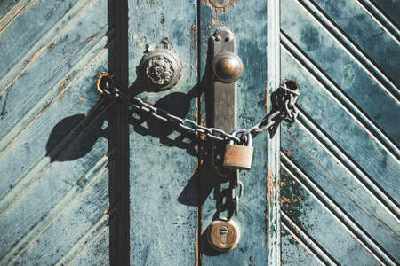 Knob and padlock on a weathered blue wooden door of an old factoryの写真素材