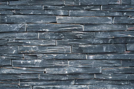 Background of an old weathered black stone wallの写真素材