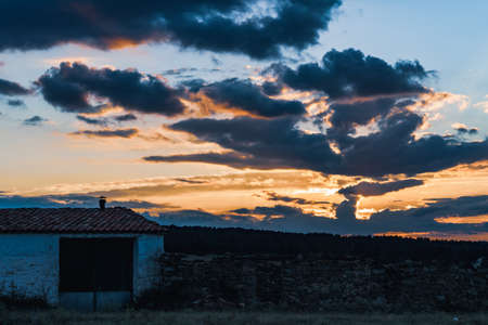 Rural landscape and cumulus clouds under the last lights of sunsetの写真素材