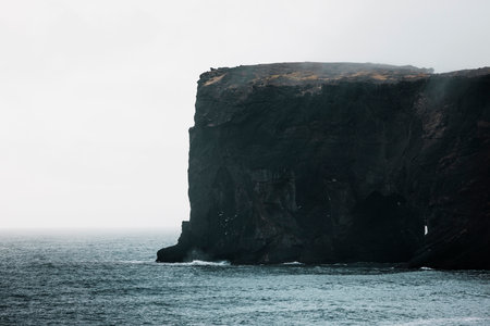 Picturesque autumn Dyrholaey Cape cliffs in fog - Exploring Icelandの写真素材