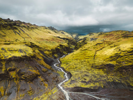 Glacier River flowing trough volcanic Icelandic landscape - cliffs and hillsの写真素材
