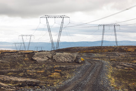 High voltage electrical cables on poles, with a backdrop of a cloudy skyの写真素材