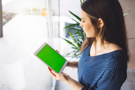 Top down view, over the head shot, woman holding a tablet with green screenの写真素材