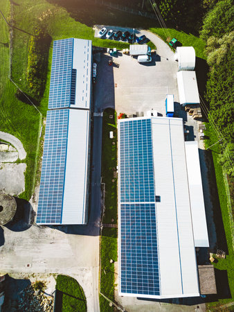 Vertical photo top down aerial view solar panels on the roof of two warehouses in the countryside