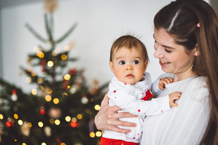 Waist up Christmas portrait of baby girl with her mom, young caucasian womanの写真素材