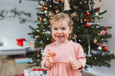 Portrait of cheerful smiling happy baby girl in pink dress on Christmas dayの写真素材