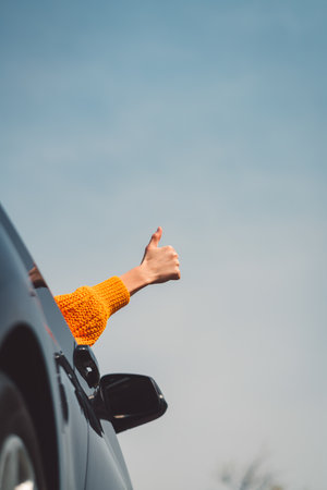 Vertical photo of persons hand sticking out the car window holding thumbs upの写真素材