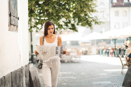 Young woman walking around the city with a map in her hands on a hot summer dayの写真素材