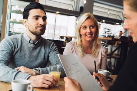Caucasian couple buying a kitchen, on a meeting with the sales person who is helping them design a kitchenの写真素材