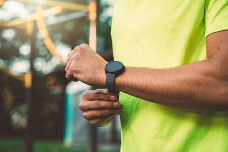 Fit man in green shirt wearing a sports watch during his run