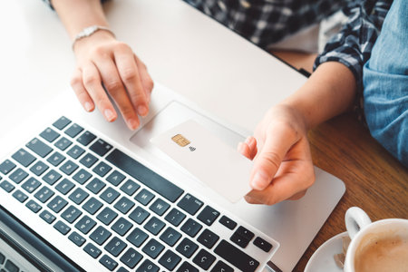 Top down view person holding a credit card over laptop keyboardの写真素材