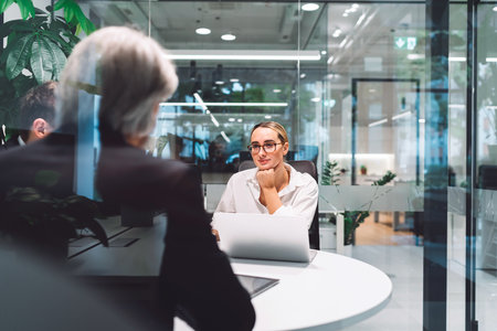 Focus on young caucasian business woman with glasses on a business meeting with her colleagues,...