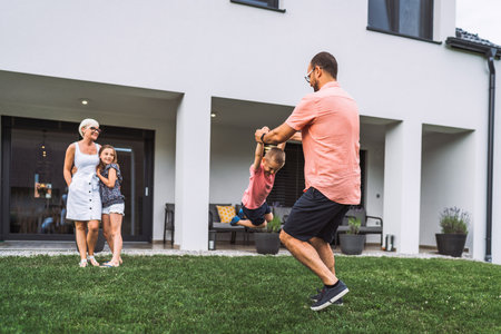 Young family spending time together on the weekends, playing games outside the house in the summerの写真素材