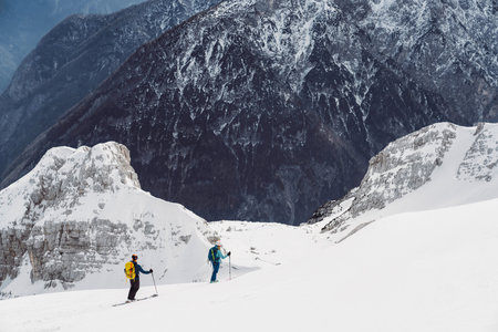 Two two tourers going down the snowy mountain, view of the mountains in the backgroundの写真素材