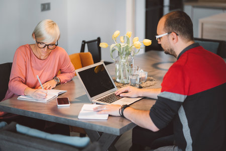 Couple working from home by the dining room tableの写真素材