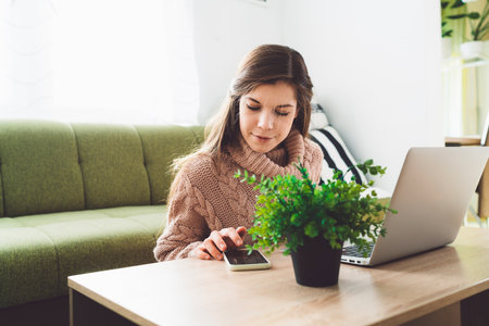 Young woman working from home in her living room with laptop on the coffee tableの写真素材