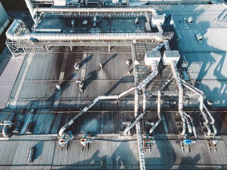 Directly above a roof top of an industrial building with ventilation pipes going across the roofの写真素材