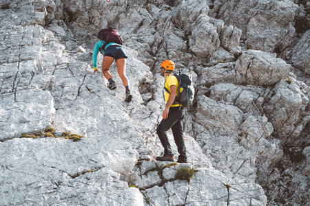Couple of mountaineers, view from the back, climing up the rocky mountain on a summer day in the Alpsの写真素材