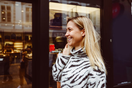 Waist up side portrait blonde woman smiling while walking around the city shoppingの写真素材