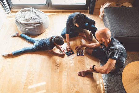Top down view young family playing on the wooden floors in the living room, little girl lying on the floorの写真素材