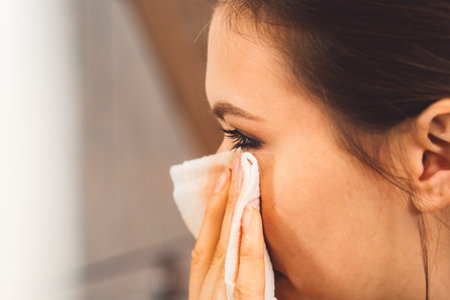 Close up side view woman cleaning her eye make up with a cotton padの写真素材
