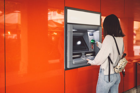 Woman inserting her card in the ATM machine, making a cash withdrawalの写真素材